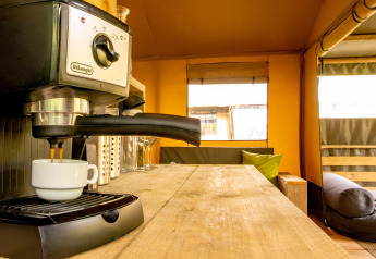 Espressomaschine auf Holztisch im Safarizelt Wood Lodge, Camping Les 3 Cantons, Frankreich, gemütliches Ambiente.