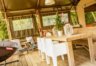 Muebles de madera y sillas blancas en la tienda safari Wood Lodge de Camping Les 3 Cantons, Francia.