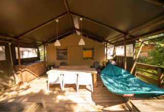Safari-Zelt Wood Lodge auf Camping Les 3 Cantons in Frankreich, mit Holzterrasse, Hängematte und Esstisch.