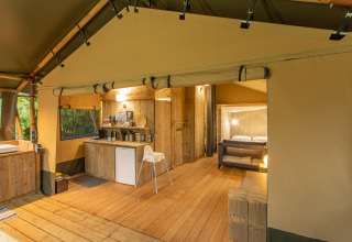 Tienda safari Wood Lodge en Camping Les 3 Cantons en Francia con suelo de madera, cocina y dormitorio.