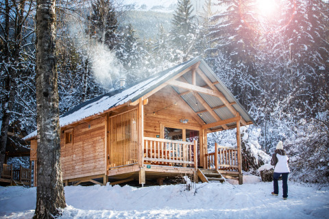 Træhytte dækket af sne i vinterskoven ved Chalet Montana, Les Chalets Huttopia de Bozel, Frankrig.