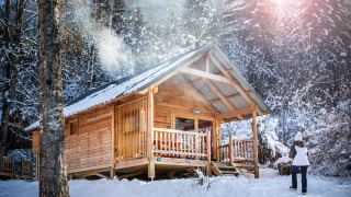 Verschneite Holzhütte im Wald bei Chalet Montana, Les Chalets Huttopia de Bozel, Frankreich.