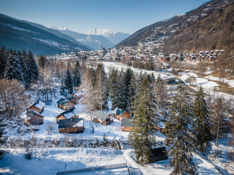 Vista invernal de Les Chalets Huttopia de Bozel, cabañas nevadas en Auvergne-Rhône-Alpes, Francia.