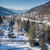 Winter view of Les Chalets Huttopia de Bozel holiday park, snowy cabins in Auvergne-Rhône-Alpes, France.