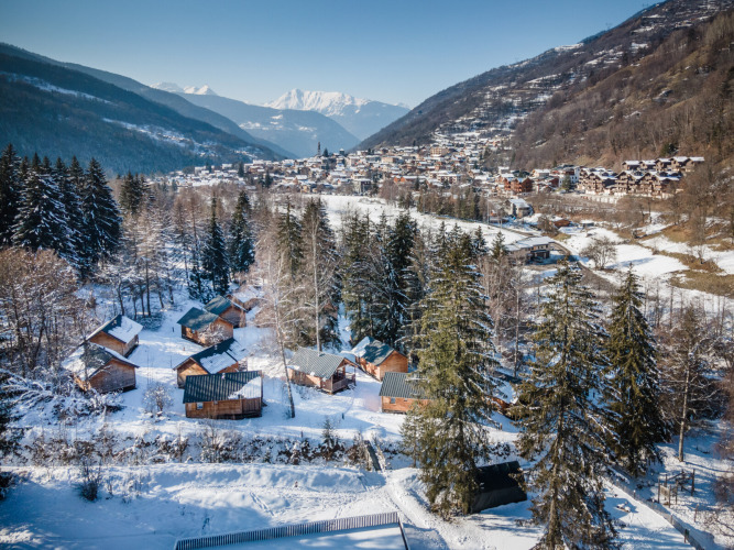 Winterliche Aussicht auf Les Chalets Huttopia de Bozel, verschneite Hütten in Auvergne-Rhône-Alpes, Frankreich.