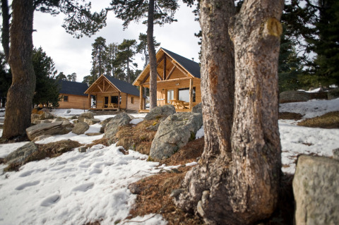 Cabañas de madera en un paisaje boscoso nevado en Les Chalets Huttopia de Font-Romeu, Occitania, Francia.
