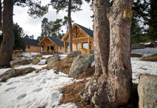 Houten chalets in een besneeuwd bosgebied bij Les Chalets Huttopia de Font-Romeu vakantiepark in Occitanië, Frankrijk.