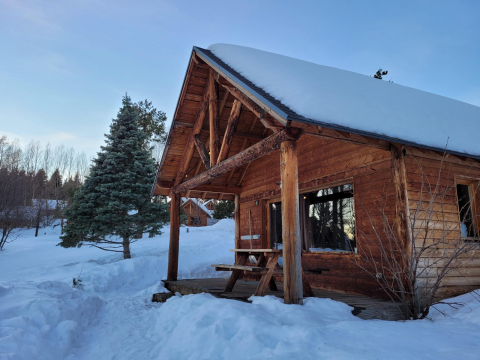 Snow-covered wooden cabin at Les Chalets Huttopia de Font-Romeu holiday park in Occitanie, France.