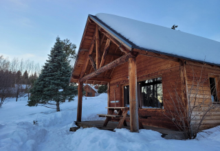 Snow-covered wooden cabin at Les Chalets Huttopia de Font-Romeu holiday park in Occitanie, France.