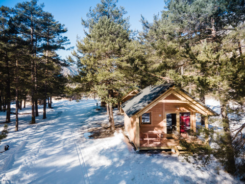 Holzhütte im verschneiten Wald bei Huttopia la Clarée, einem Ferienpark in Provence-Alpes-Côte d’Azur, Frankreich