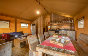 Interior view of a Safari tent at Campo dei Fiori, Italy, featuring rustic wooden decor and dining area.