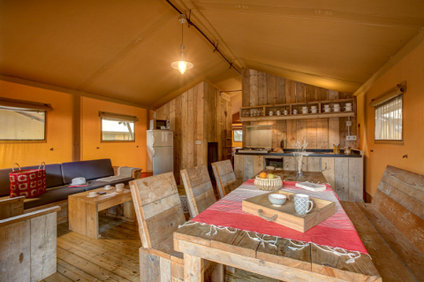 Binnenaanzicht van de Safaritent bij Campo dei Fiori, Italië, met rustiek houten interieur en eethoek.