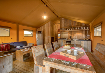 Interior view of a Safari tent at Campo dei Fiori, Italy, featuring rustic wooden decor and dining area.