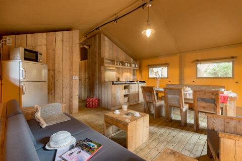 Interior de la tienda Safari tent en Campo dei Fiori (Glamping4all) en Italia con muebles de madera rústica.