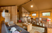 Interior of Safari tent at Campo dei Fiori (Glamping4all) in Italy, showcasing rustic wood furniture.