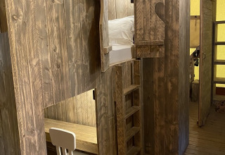 Houten interieur van een safaritent op Campo dei Fiori met stapelbed, ladder en een bureauhoekje.