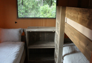Vista interna di una tenda safari con letto a castello, letto singolo e mobili in legno, Campo dei Fiori, Italia.