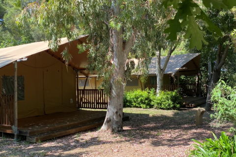 Safari-telt på Campo dei Fiori (Glamping4all) i Italien med veranda, træer og grøn natur omkring.
