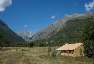 Tenda al parco vacanze Huttopia Vallouise circondata da montagne e verde in Provenza-Alpi-Costa Azzurra, Francia.