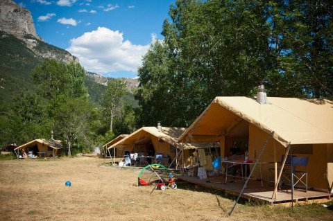 Tiendas de safari en Huttopia Vallouise, parque vacacional en Provence-Alpes-Côte d’Azur, rodeado de montañas.