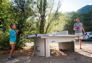 Billede af en mand og en dreng, der spiller bordtennis udenfor på Huttopia Vallouise, Provence-Alpes-Côte d’Azur.
