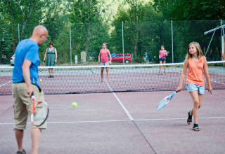 Familier spiller tennis sammen på en udendørs bane omgivet af grønne træer i Provence-Alpes-Côte d'Azur.