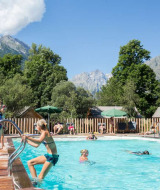 Piscina exterior en Huttopia Vallouise con huéspedes disfrutando y vistas a las montañas de Provenza-Alpes-Costa Azul.