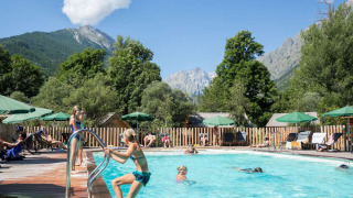 Piscina exterior en Huttopia Vallouise con huéspedes disfrutando y vistas a las montañas de Provenza-Alpes-Costa Azul.
