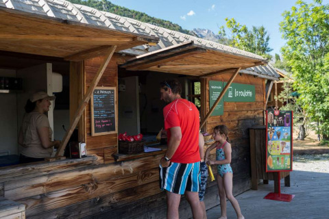 Feriegæster bestiller snacks ved en træbod på Huttopia Vallouise, Provence-Alpes-Côte d’Azur, Frankrig.