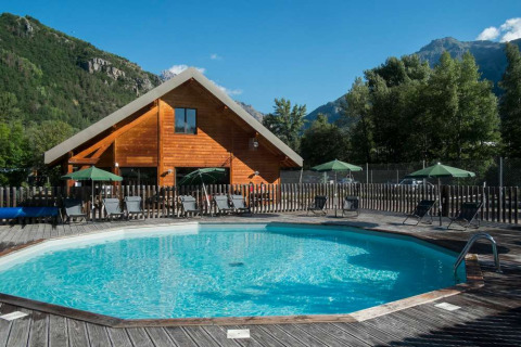 Piscina al aire libre y tumbonas frente a una cabaña en Huttopia Vallouise, Provence-Alpes-Côte d’Azur, Francia.