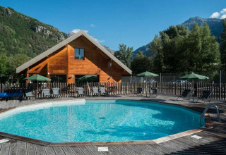 Udendørs pool foran en træhytte i bjergene ved Huttopia Vallouise feriepark i Provence-Alpes-Côte d’Azur, Frankrig.