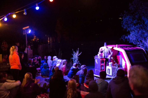 Avondvoorstelling in openlucht met publiek bij vakantiepark Huttopia Vallouise in Frankrijk.
