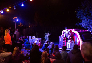 Avondvoorstelling in openlucht met publiek bij vakantiepark Huttopia Vallouise in Frankrijk.