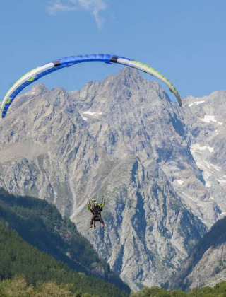 Parapente sobre un valle verde con imponentes montañas cerca de Vallouise, en Provence-Alpes-Côte d’Azur, Francia.