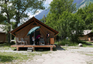 Familie entspannt auf der Terrasse einer Hütte im Huttopia Vallouise, umgeben von Natur und Bergen.