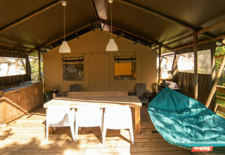 Safari Lodge + Teeny Lodge: terraza de madera con mesa, silla hamaca y cocina exterior en Camping Les 3 Cantons.