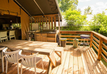 Terrasse extérieure de la tente Safari Lodge au Camping Les 3 Cantons en France, cuisine et coin repas en bois.
