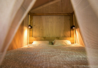 Interior view of a cozy sleeping area inside a Safari Lodge tent at Camping Centro Vacanze San Marino.