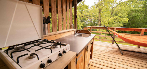 Cuisine extérieure avec gazinière, évier et hamac sur terrasse en bois à la Safari Lodge, Camping Centro Vacanze San Marino.