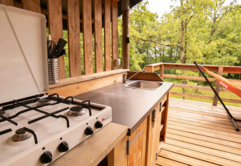 Outdoor kitchen with gas stove, sink, and hammock on wooden deck at Safari Lodge, Camping Centro Vacanze San Marino.
