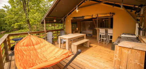 Tenda Safari Lodge al Camping Centro Vacanze San Marino con terrazza in legno, amaca arancione e zona pranzo.