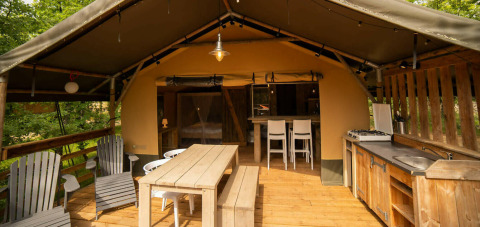 Tenda Safari Lodge al Camping Centro Vacanze San Marino con terrazza in legno, tavolo e cucina all'aperto.