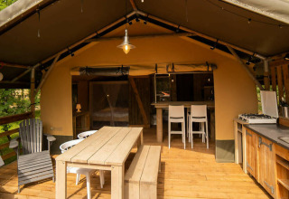 Tenda Safari Lodge al Camping Centro Vacanze San Marino con terrazza in legno, tavolo e cucina all'aperto.
