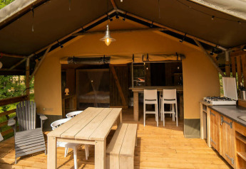 Safari Lodge tent at Camping Centro Vacanze San Marino featuring wooden deck, dining area, and kitchen.