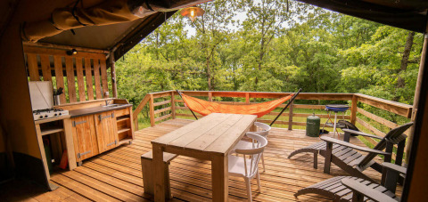 Terrazza in legno con amaca, cucina esterna e sedie presso Safari Lodge, Camping San Marino.