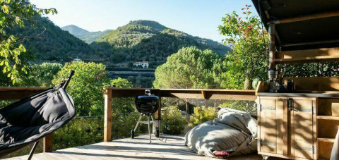 Terrazza all’aperto a Isolabona, Liguria, con vista monti, barbecue, poltrona sospesa e comodi pouf.