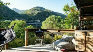 Outdoor terrace in Isolabona, Liguria, Italy, offering mountain views, a grill, hammock chair, and bean bags.