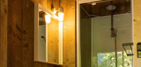Baño en tienda Safari lodge en Camping Delle Rose, con espejo iluminado y cabina de ducha moderna.