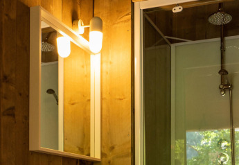 Baño en tienda Safari lodge en Camping Delle Rose, con espejo iluminado y cabina de ducha moderna.