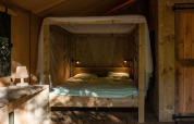 Interior de una tienda Safari Lodge en Camping Delle Rose, Italia, con cama doble y decoración de madera.